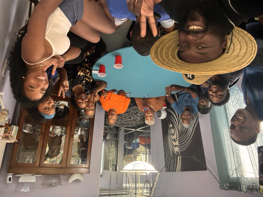 Joe Smith in a straw hat with neighbors around a table at a community gathering